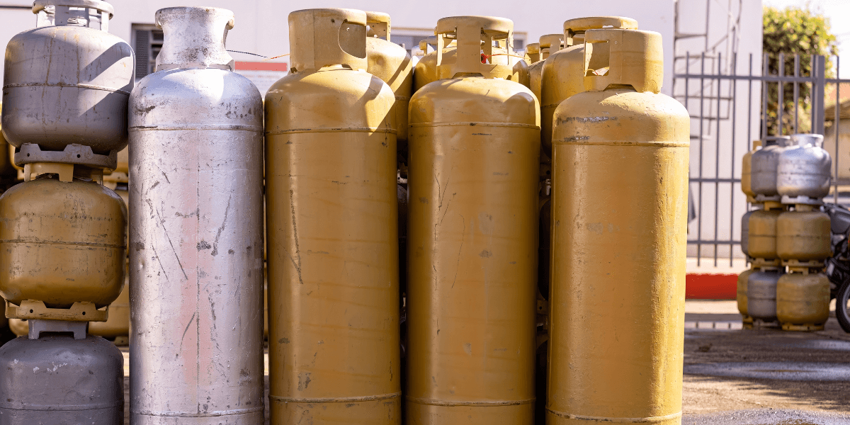 Gold and silver compressed gas cylinders stacked next to each other in an industrial yard